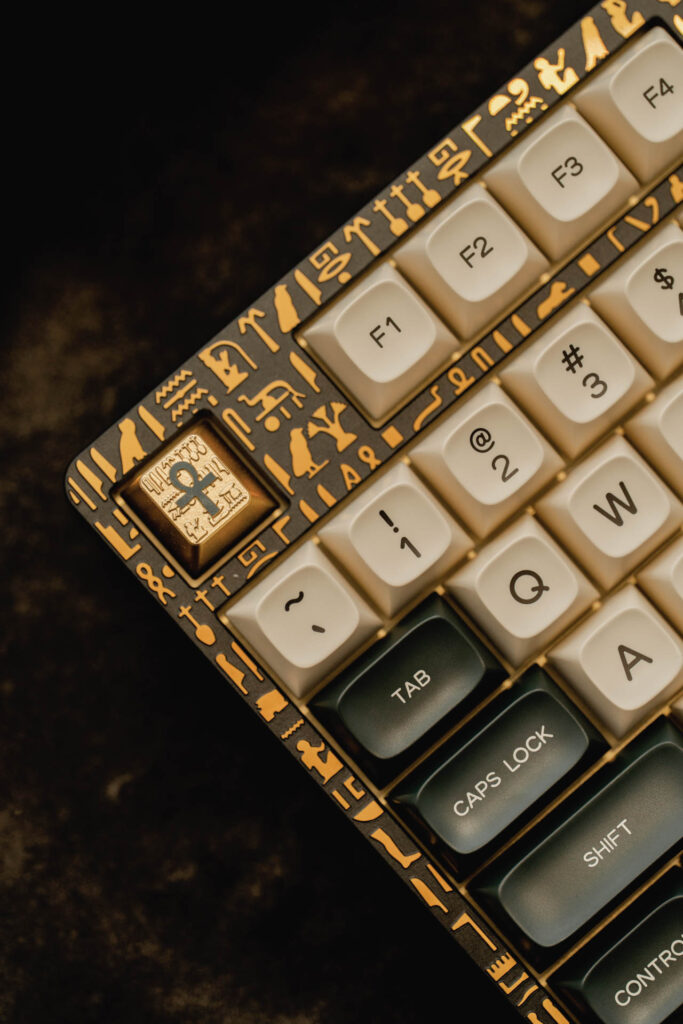 Custom mechanical keyboard with gold hieroglyphic accents, cream and dark green keycaps and a gold Anubis artisan key